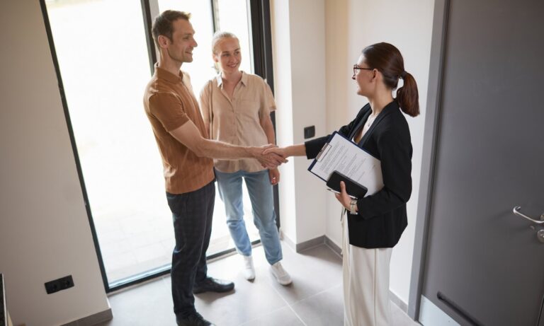 Estate agent greeting a couple inside a bright modern home