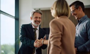 Estate agent shaking hands with a couple inside a modern home